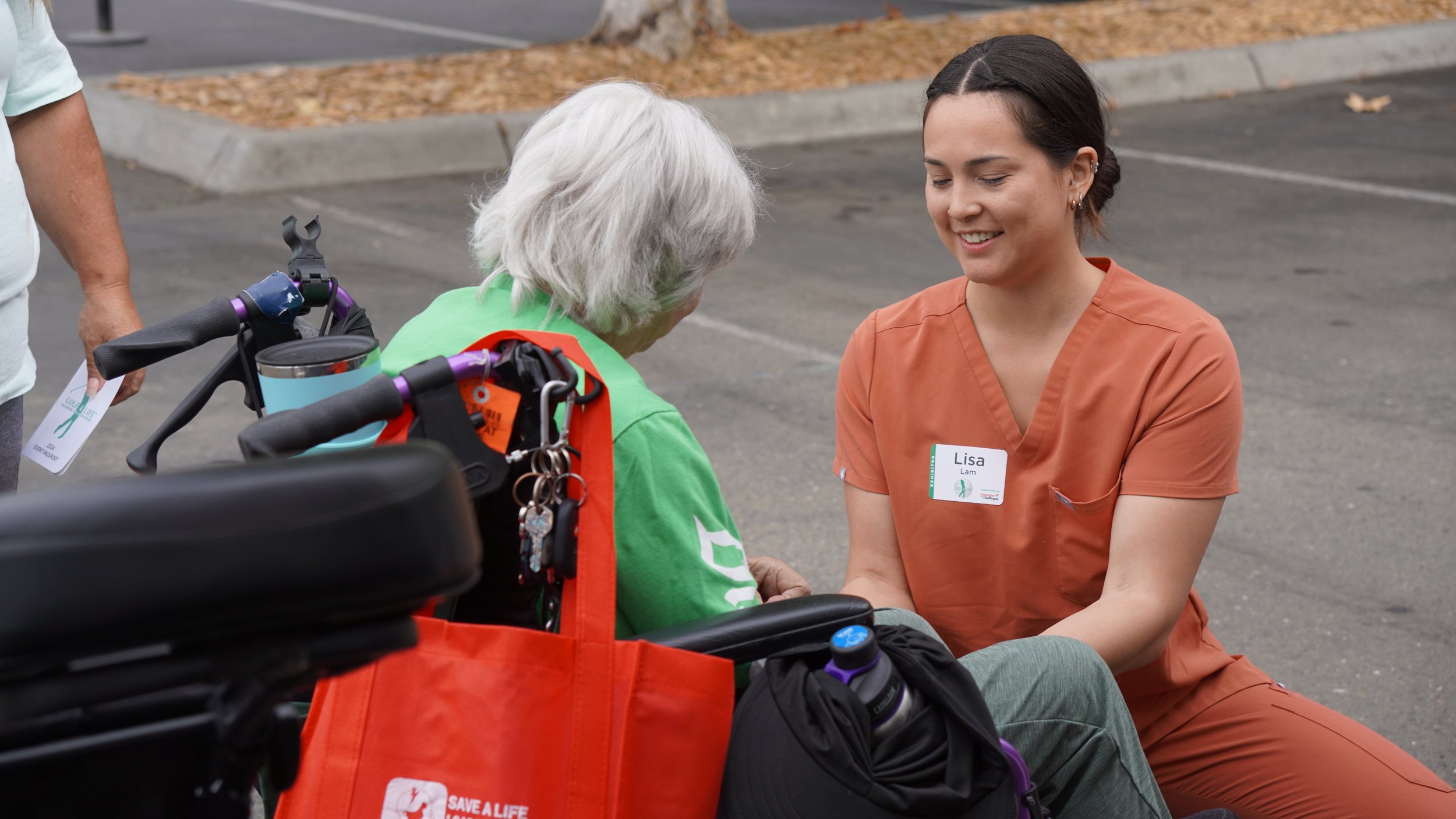 HOPE therapist kneeling to assist elderly woman at community outreach event