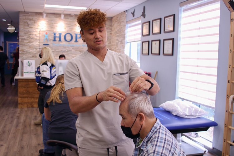 Therapist performing scalp acupuncture needle placement on patient in treatment room
