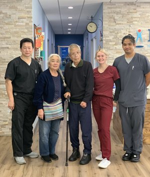 Dr. Lu, elderly patient with cane, and staff posing in clinic hallway
