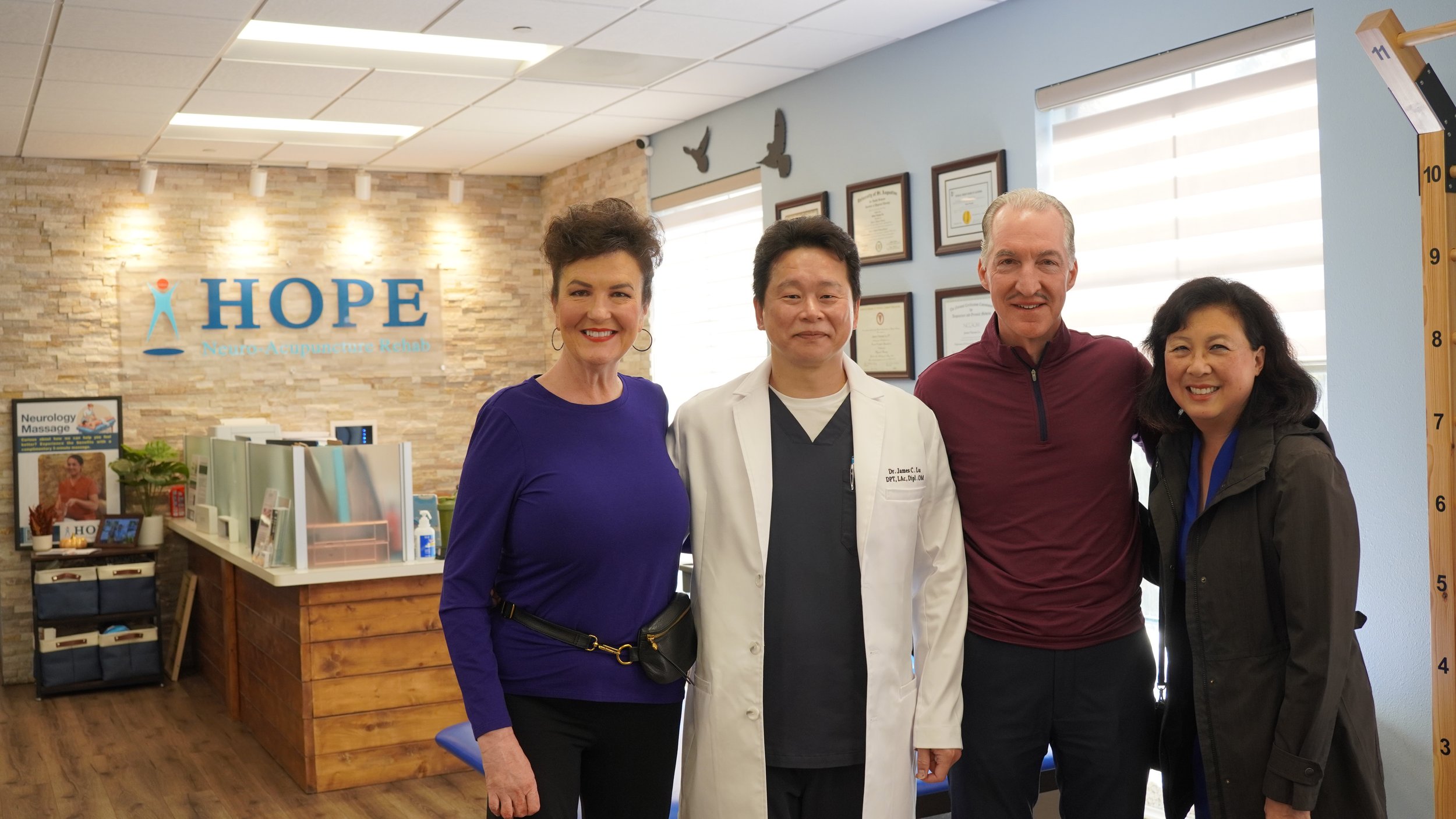Dr. Lu with patient couple and staff member smiling in HOPE Clinic treatment area