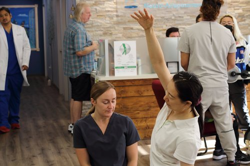 Therapist demonstrating arm range of motion exercise with patient at clinic reception