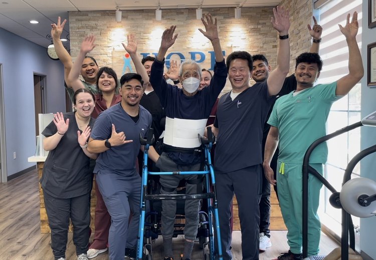 HOPE Clinic team celebrating patient recovery milestone with arms raised in lobby