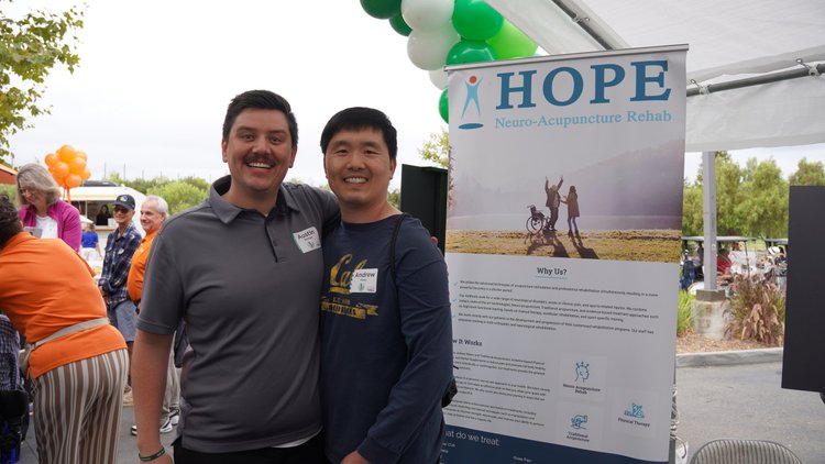 HOPE Clinic team members smiling at community outreach event next to banner