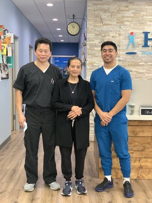 Dr. Lu and therapist posing with patient in clinic hallway