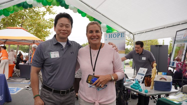 Dr. Lu posing with community supporter at HOPE Clinic booth