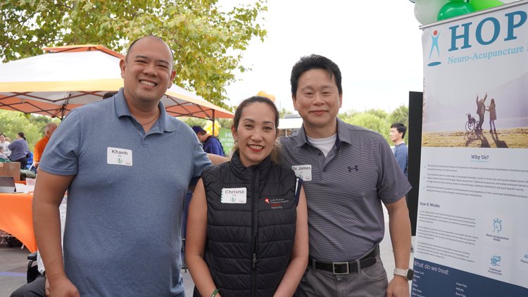 Three community partners posing at HOPE Clinic stroke awareness event booth
